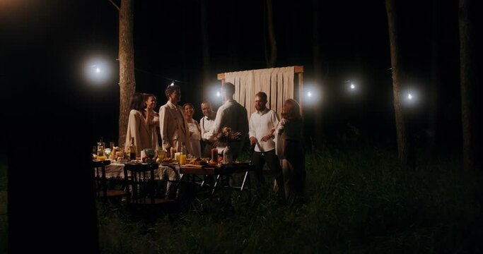 Elegant guests smile and dance at an outdoor party at night