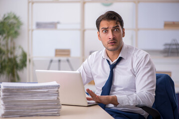 Fototapeta premium Young male employee and too much work in the office