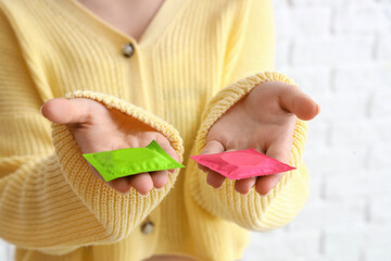 Young woman with condoms on white brick background, closeup