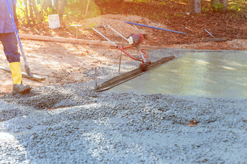 Worker on building site are leveling concrete for driveway with slump concrete trowel