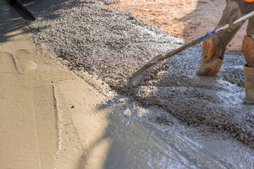 Workers in construction site with slump concrete ready mix trowel leveling concrete for driveway