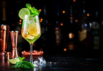 Hugo spritz alcoholic cocktail drink with dry sparkling wine or prosecco, elderflower syrup, soda, lime, mint and ice, dark bar counter background - obrazy, fototapety, plakaty
