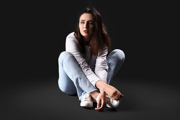 Female drug addict sitting on black background