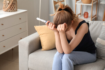 Upset young woman with pregnancy test at home