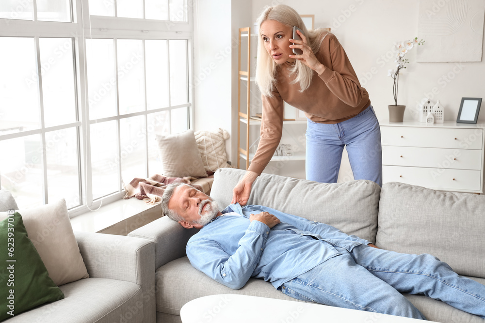 Poster mature woman calling ambulance while her husband having heart attack at home