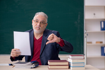 Old male teacher sitting in the classroom