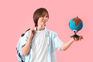 Male student with globe on pink background