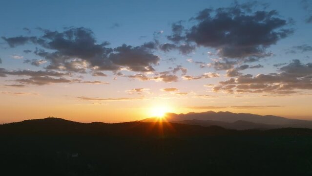 Aerial view of sun setting over San Bernardino Mountains in area of Lake Arrowhead, Los Angeles, California, USA. Drone shot of magic sunset with clouds on colorful sky. Natural background, 4k footage