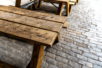 Wood picnic tables in a cobblestone street - 623945853