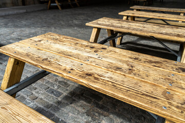 Wood picnic tables in a cobblestone street. - 623945872