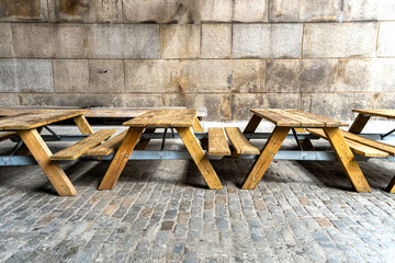 Wood picnic tables in a cobblestone street. - 623945890