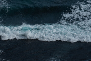 The waves of the ocean water meet with underwater pointed rocks