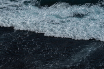 The waves of the ocean water meet with underwater pointed rocks