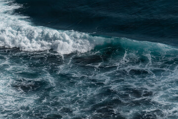 The waves of the ocean water meet with underwater pointed rocks