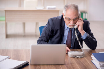 Old male employee working in the office