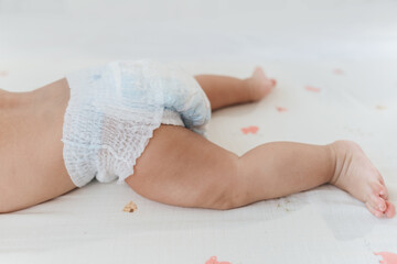 Cute infant baby in white nappy on bed. Top view. Diaper change and baby care. Baby healthcare...