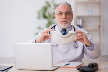 Old male doctor holding neck brace in the clinic