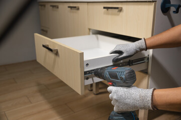 Worker fix over tight drawer slides in kitchen. Concept Fix stuck wooden drawer slides.