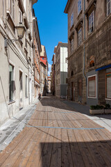 The street of the old town, the paving stones are covered with wooden flooring. Facades of old and colorful Mediterranean houses. Trieste, Italy