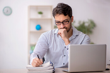 Fototapeta premium Young male employee student working in the office