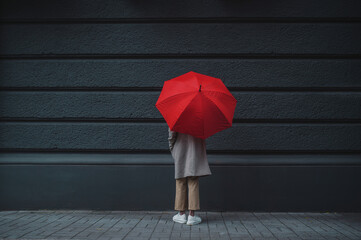 An unrecognizable woman under a red umbrella without a face stands with her back on the sidewalk. rainy weather. Concept of sadness, loneliness and depression © illustrissima