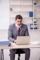 Young male employee after car accident sitting in the office