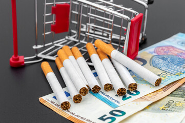 Cigarettes with shopping cart and euro on black. - 623969287