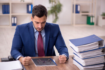 Young male employee and too much work in the office