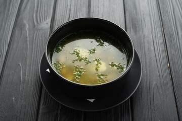 Plate of chicken, vegetables, and noodles soup, shot from above on a dark rustic texture, top view