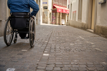 person in wheelchair on cobbled street in old own