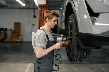 Professional man mechanic changing car wheel using electric drill