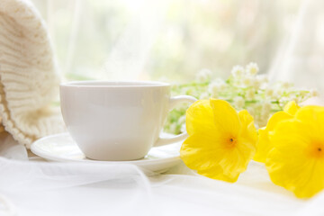 Coffee morning.  White steaming cup of hot coffee for relax after working hobbies crochet on white wooden near window with flowers