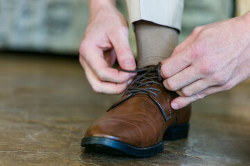 man tighten the shoelaces on his brown shoes