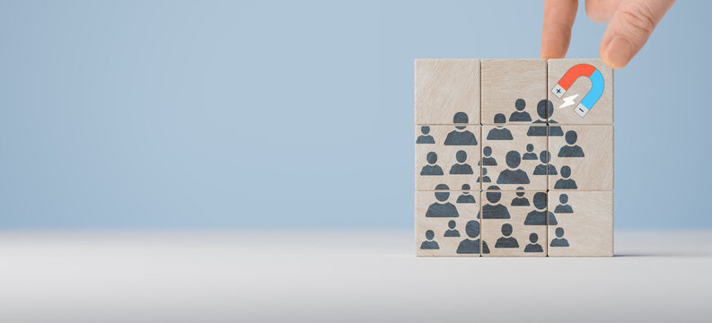 Attracting online customer and lead generation concept. Digital inbound marketing, customer retention strategy. Hand hold wooden cube with icon big magnet to attract many people on blue background.
