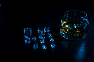Glass with cognac and ice on a dark background. the concept of alcoholism and drinking
