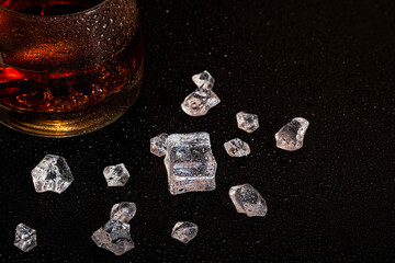 Glass with cognac and ice on a dark background. the concept of alcoholism and drinking