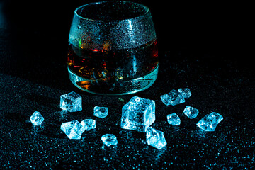 Glass with cognac and ice on a dark background. the concept of alcoholism and drinking