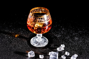 Glass with cognac and ice on a dark background. the concept of alcoholism and drinking