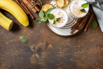 Banana smoothie with cinnamon in drinking glass on a wooden background. Detox menu. View from above. Copy space.