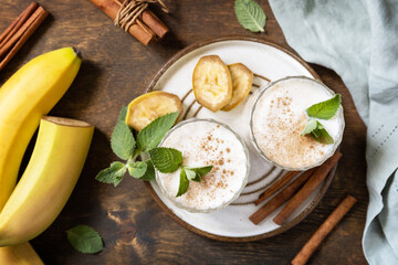 Banana smoothie with cinnamon in drinking glass on a wooden background. Detox menu. View from above.