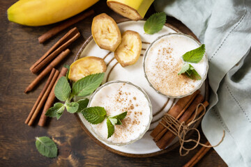 Detox menu. Banana smoothie with cinnamon in drinking glass on a wooden background. View from above.