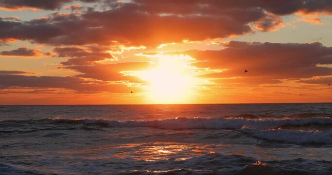 Tropical sunrise with dramatic clouds and sun rays over ocean waves and caribbean sea, seascape horizon 4K video