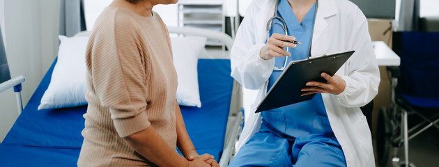  Doctor and senior  female patient who lie on the bed while checking pulse, consult and explain...