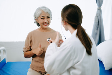 Obraz premium Friendly Female Head Nurse Making Rounds does Checkup on Patient Resting in Bed. She Checks tablet while Man Fully Recovering after Successful Surgery in hospital.