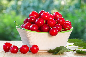 Fototapeta na wymiar Fresh ripe cherry berries in a bowl on a wooden table outdoors
