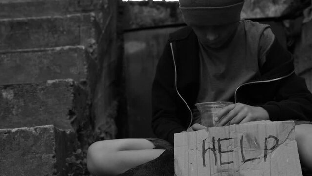 Beggar.Homeless boy or teenager begs for alms.Black and white video