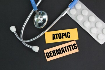 Stethescopes, medicines and colored paper with the word atopic dermatitis. the concept of illness...