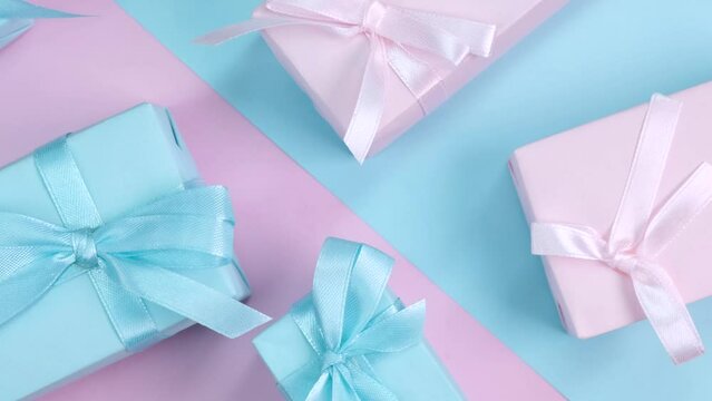Rotating background with colorful pink and blue gift boxes with ribbons and bows in pastel colors on a pink background, birthday concept, boy or girl