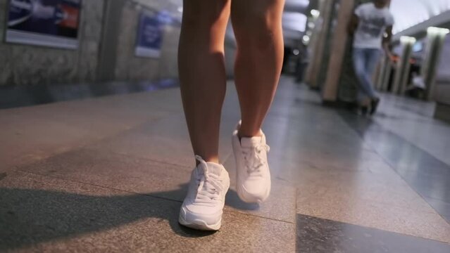 A young woman in sportswear walks on the platform of an underground subway station