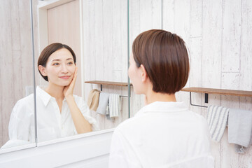 Fototapeta premium 洗面室でスキンケアをするミドルエイジの女性